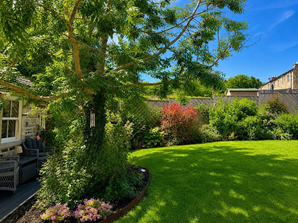 A garden with a tree and furniture at The Summerhouse in Kildwick