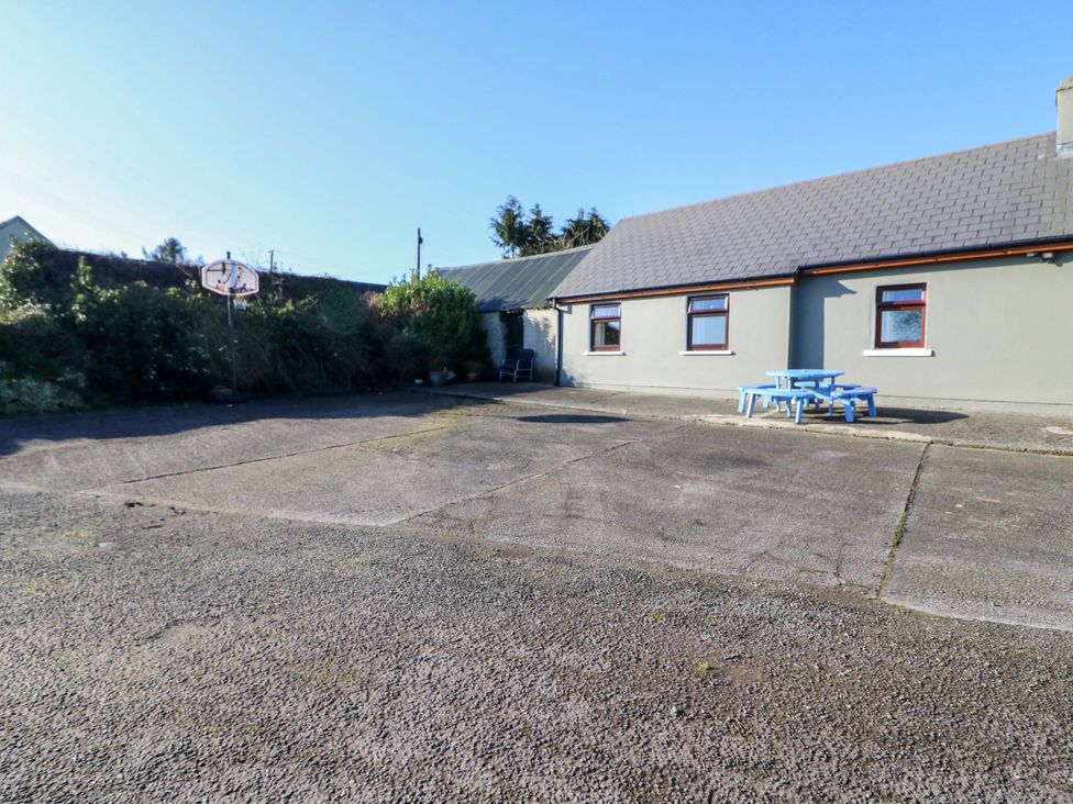 An outdoor area with a basketball hoop and blue tables at Thadg and Hannah’s in Miltown
