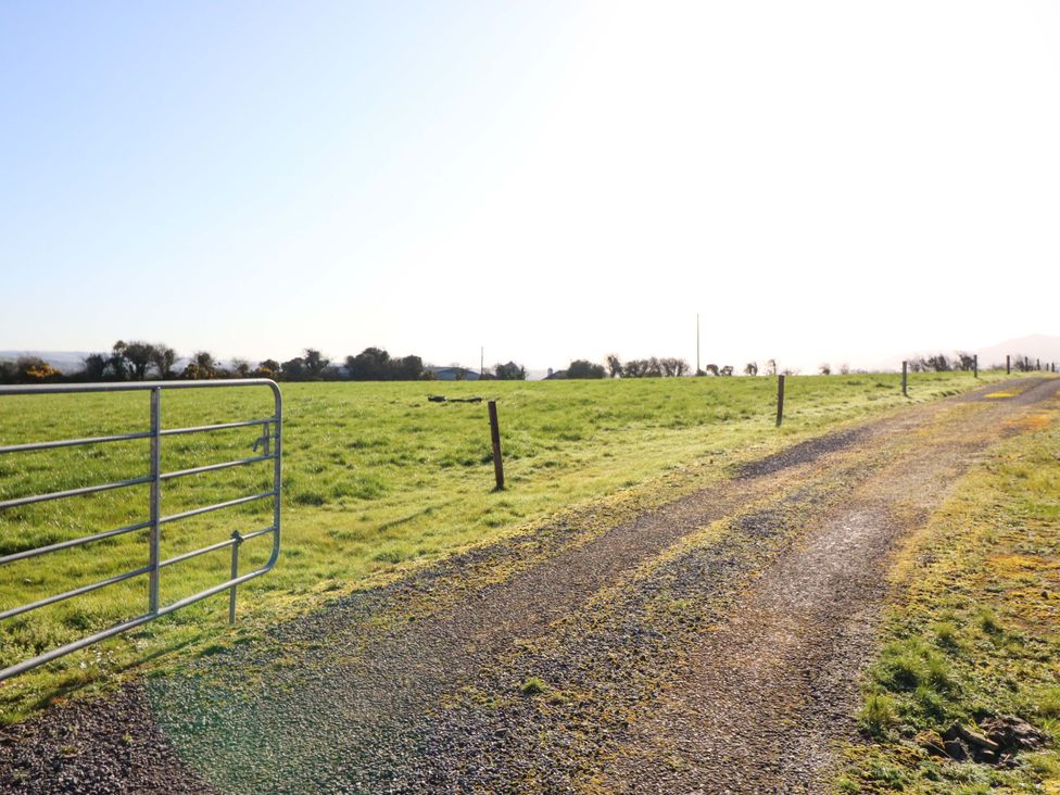 A grassy field with a gate and gravel path at Thadg and Hannah’s in Miltown
