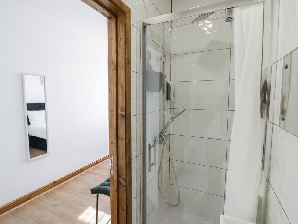A bathroom showing a shower and a mirror at JMG House in West Bromwich