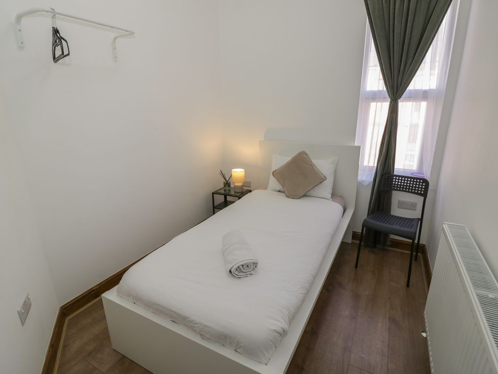 A bedroom with a single bed and bedside table at JMG House in West Bromwich