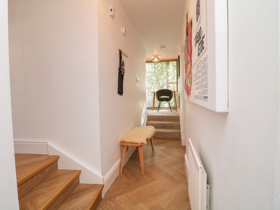 A hallway with stairs, a bench, and wall art at Tower Cottage Nottingham