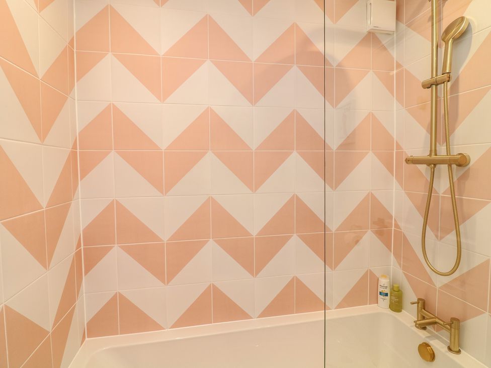 A bathroom with a shower and pink patterned tiles at Tower Cottage Nottingham