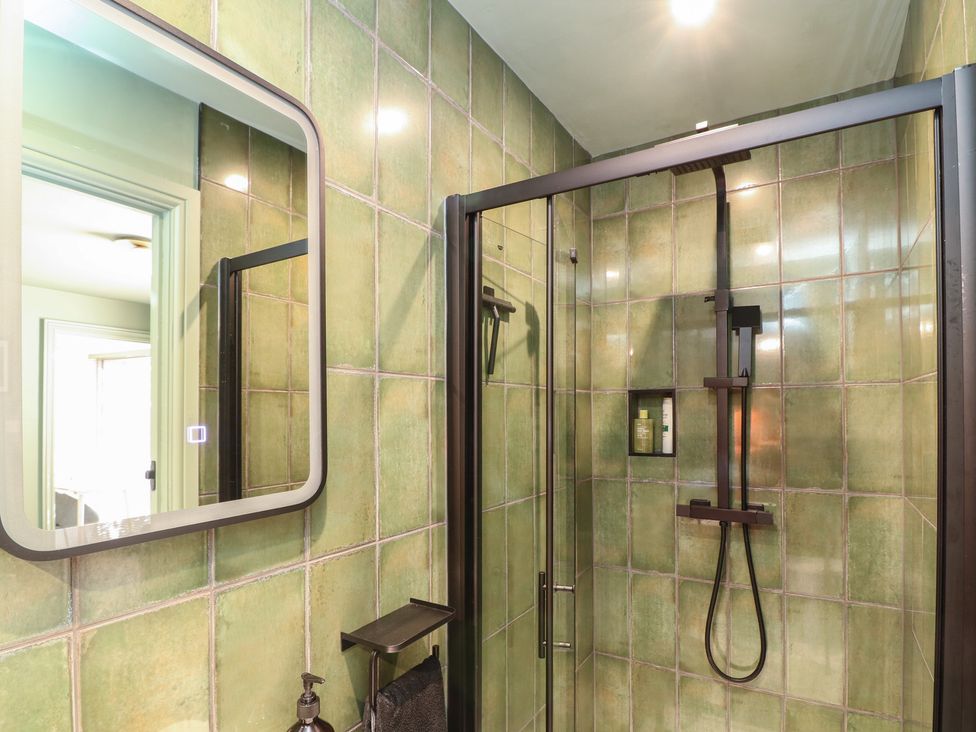 A bathroom with a shower and mirror at Tower Cottage in Nottingham