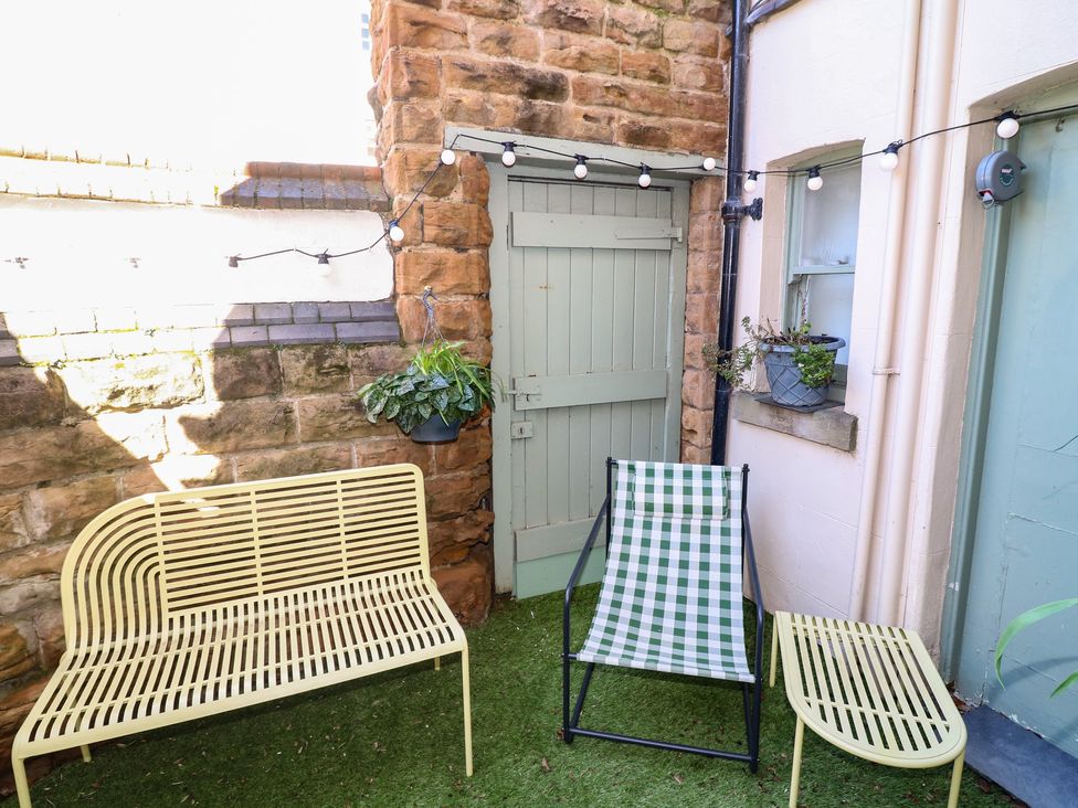 An outdoor seating area with a bench, chair, and plants at Tower Cottage in Nottingham