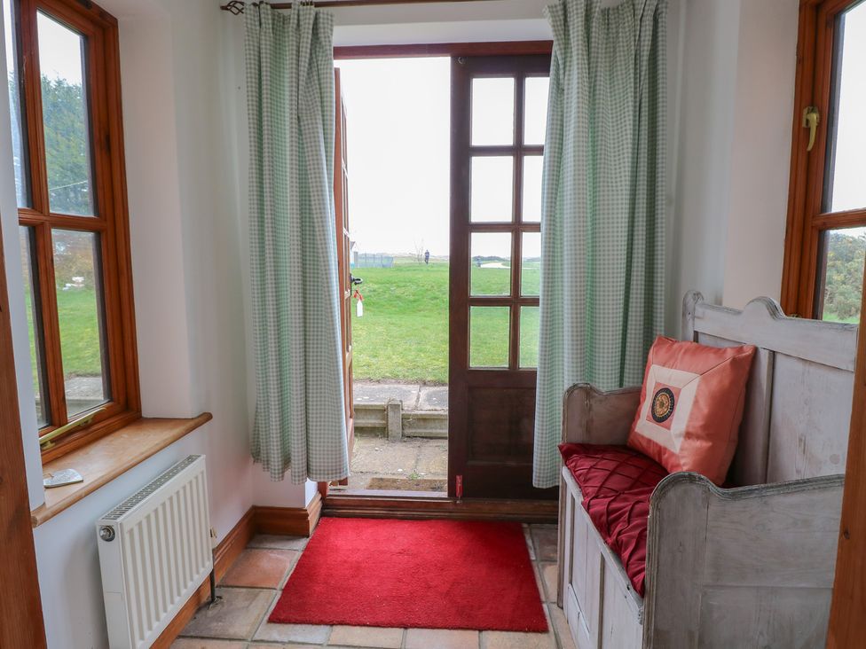 An entrance with a bench and door leading to a garden at Mabby in Caister-On-Sea
