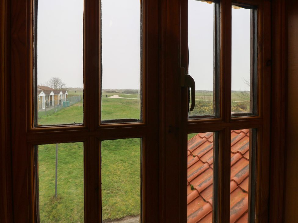 A view from a window showing grass, houses, and a path at Mabby in Caister-On-Sea
