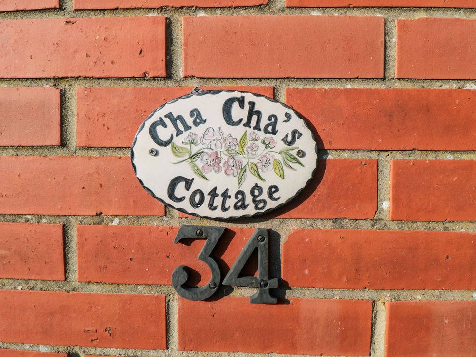 A nameplate and number sign on a brick wall at Cha Cha's Cottage Whitby