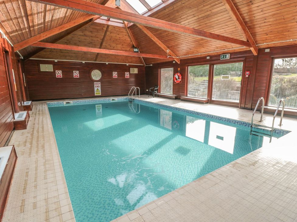 An indoor swimming pool with large windows at Cha Cha's Cottage in Whitby
