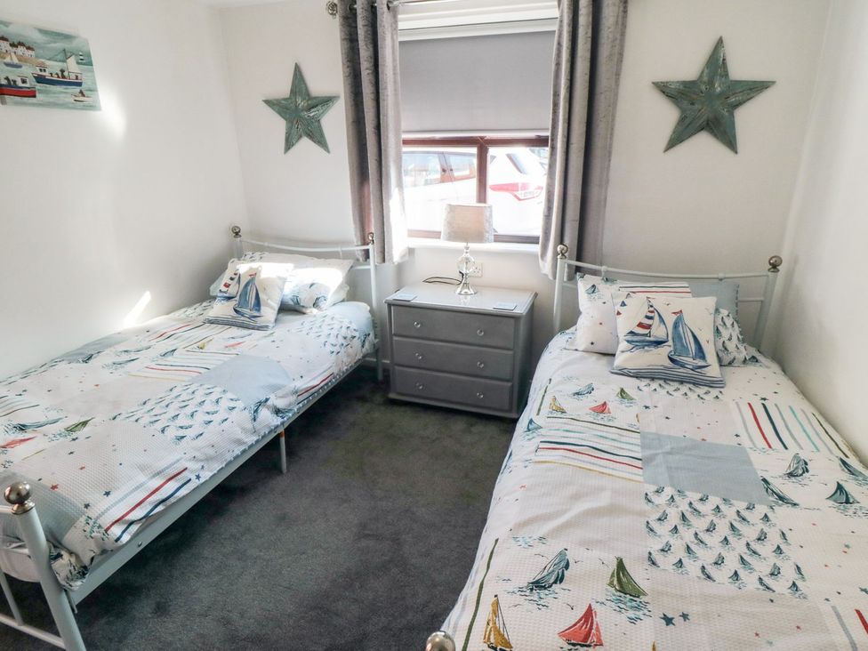 A bedroom with two beds and a bedside table at Cha Cha's Cottage in Whitby