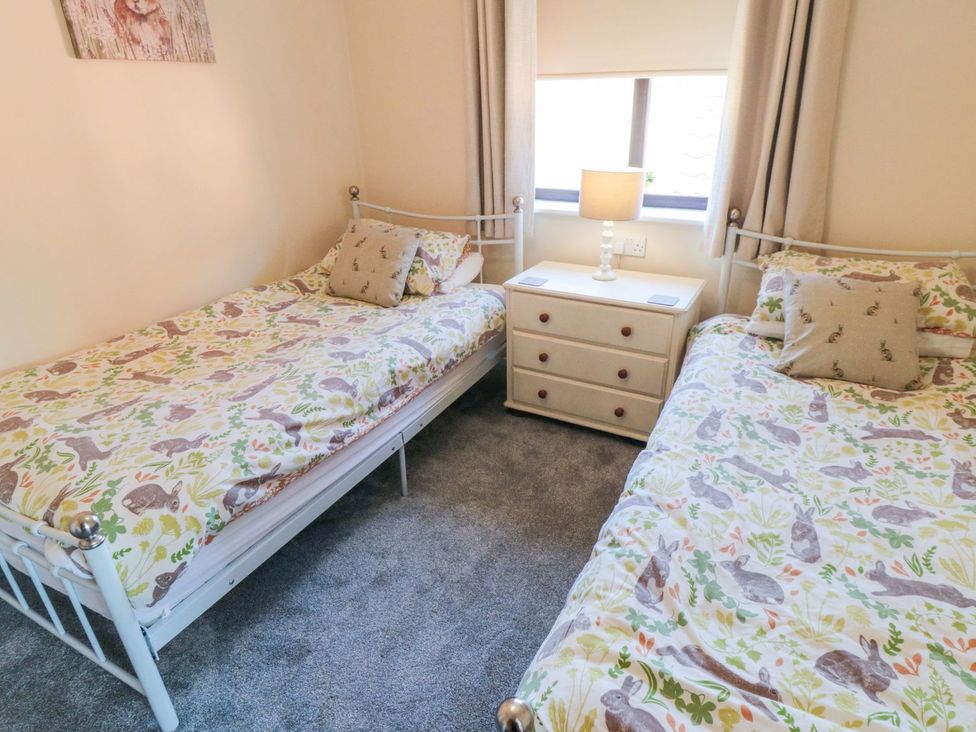 A bedroom with two beds and a nightstand at Cha Cha's Cottage in Whitby