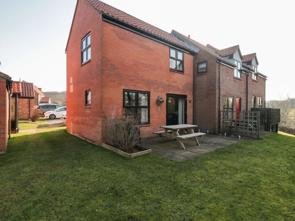 A brick house with patio furniture in the garden at Cha Cha's Cottage in Whitby