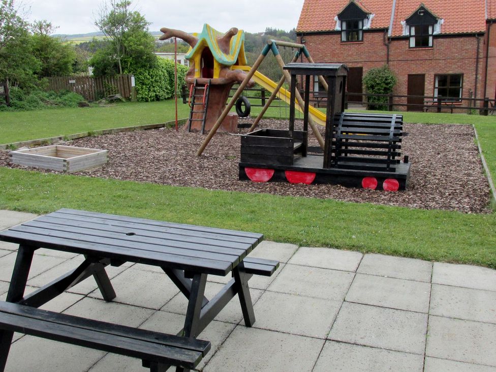 An outdoor area with playground equipment and a picnic table at Cha Cha's Cottage in Whitby