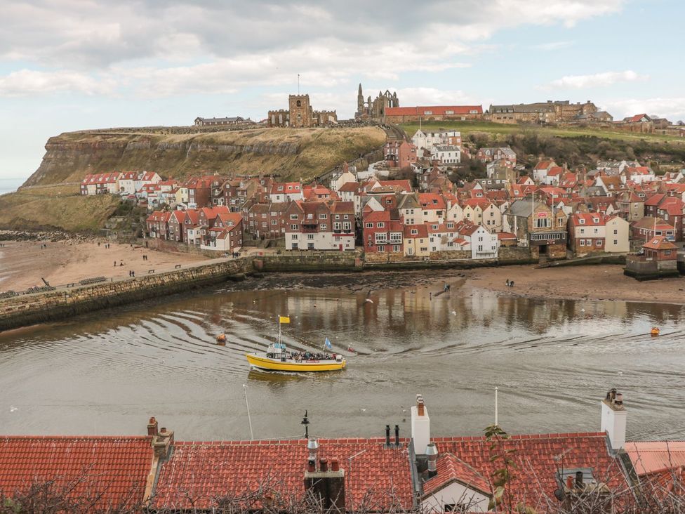 A view of a coastal area with buildings and a boat at Cha Cha's Cottage in Whitby