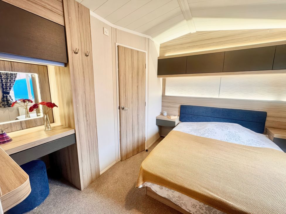 A bedroom with a bed and vanity table at Chappies Caravan 2.0 Rhyl