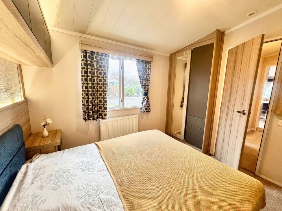 A bedroom with a bed and window at Chappies Caravan 2.0 in Rhyl