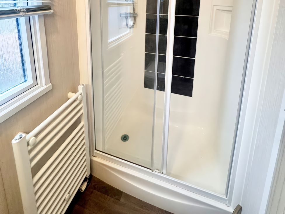 A shower enclosure with a radiator and window at Chappies Caravan 2.0 Rhyl