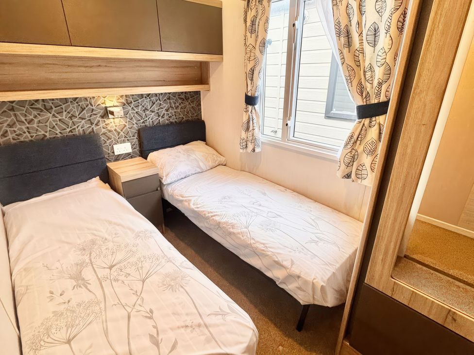 A bedroom with twin beds and a bedside table at Chappies Caravan 2.0 in Rhyl