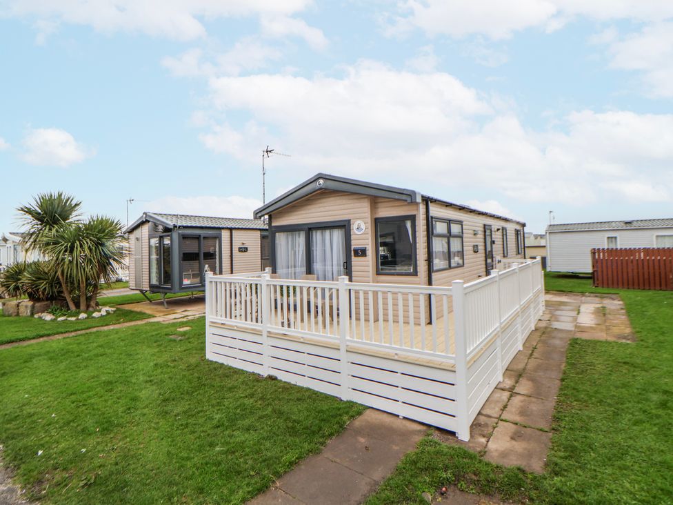 A caravan with decking and a fence at Chappie's Caravan 2.0 Rhyl
