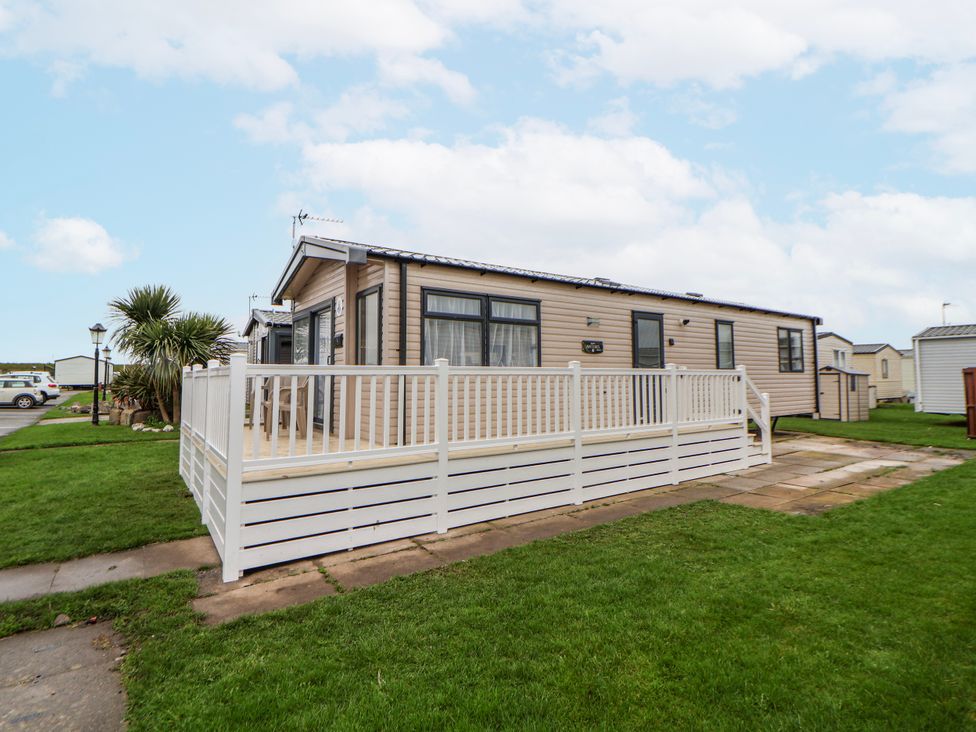 A caravan with a deck and grass area at Chappie's Caravan 2.0 in Rhyl