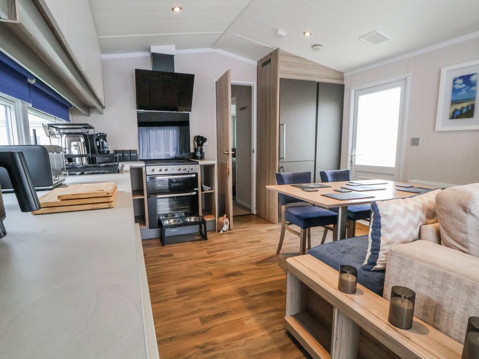 A kitchen with appliances and dining area at Chappie's Caravan 2.0 in Rhyl