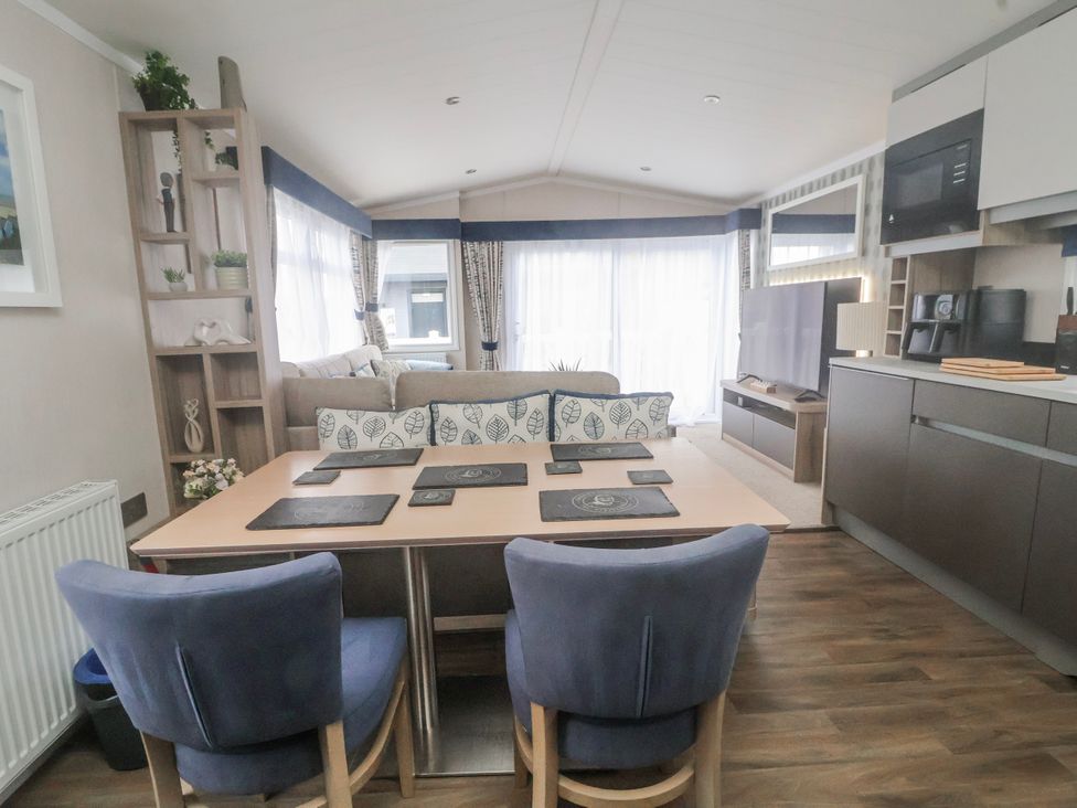 A living room with a sofa and dining area at Chappie's Caravan 2.0 in Rhyl