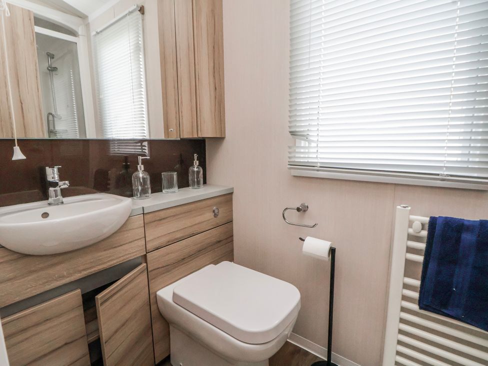 A bathroom with a sink, toilet and storage at Chappie's Caravan 2.0 in Rhyl