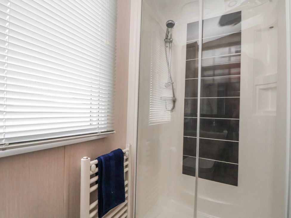 A shower area with a blue towel hanging at Chappie's Caravan 2.0 Rhyl