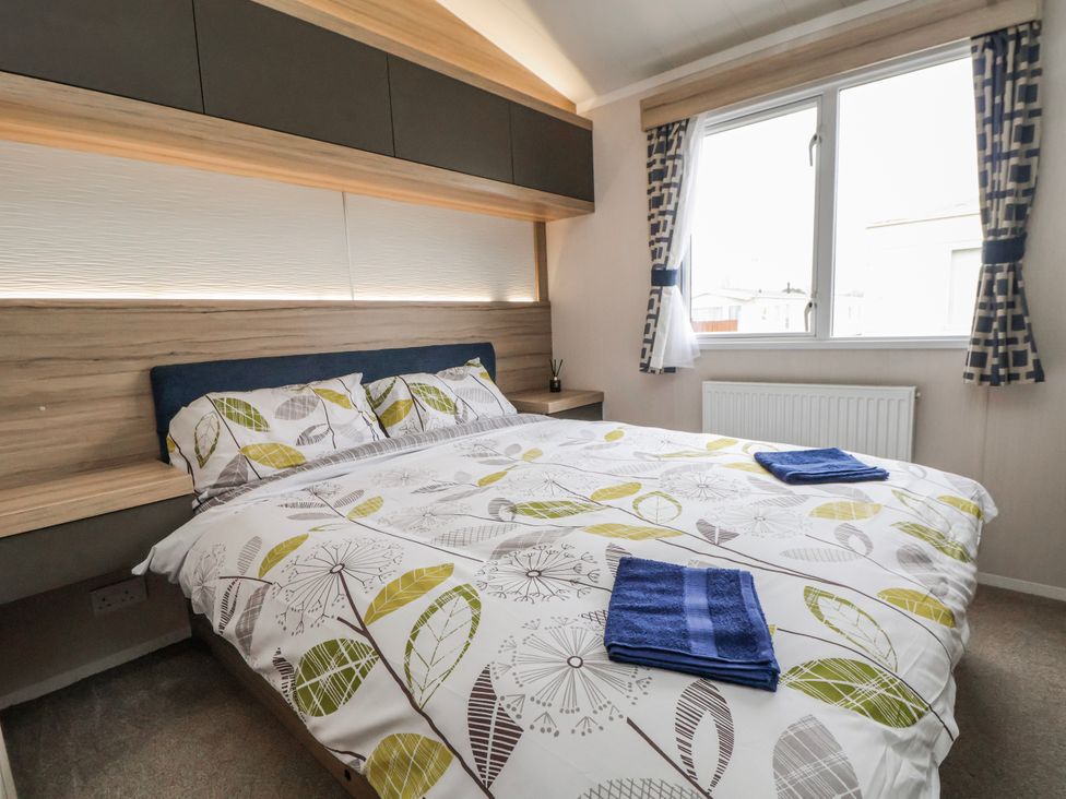 A bedroom with a double bed and window at Chappie's Caravan 2.0 Rhyl