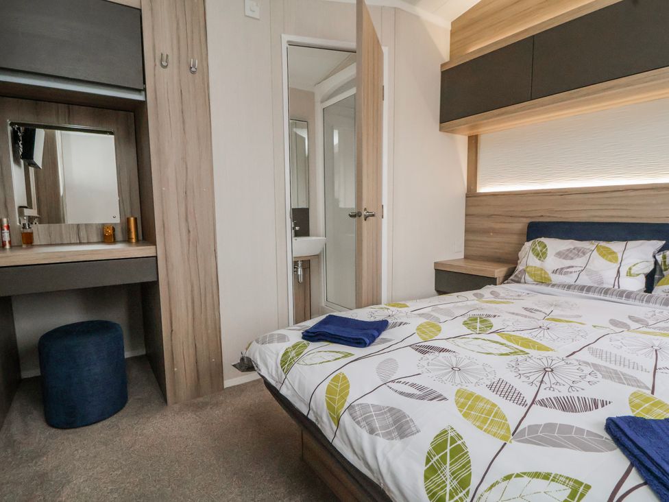 A bedroom with a bed and vanity at Chappie's Caravan 2.0 in Rhyl