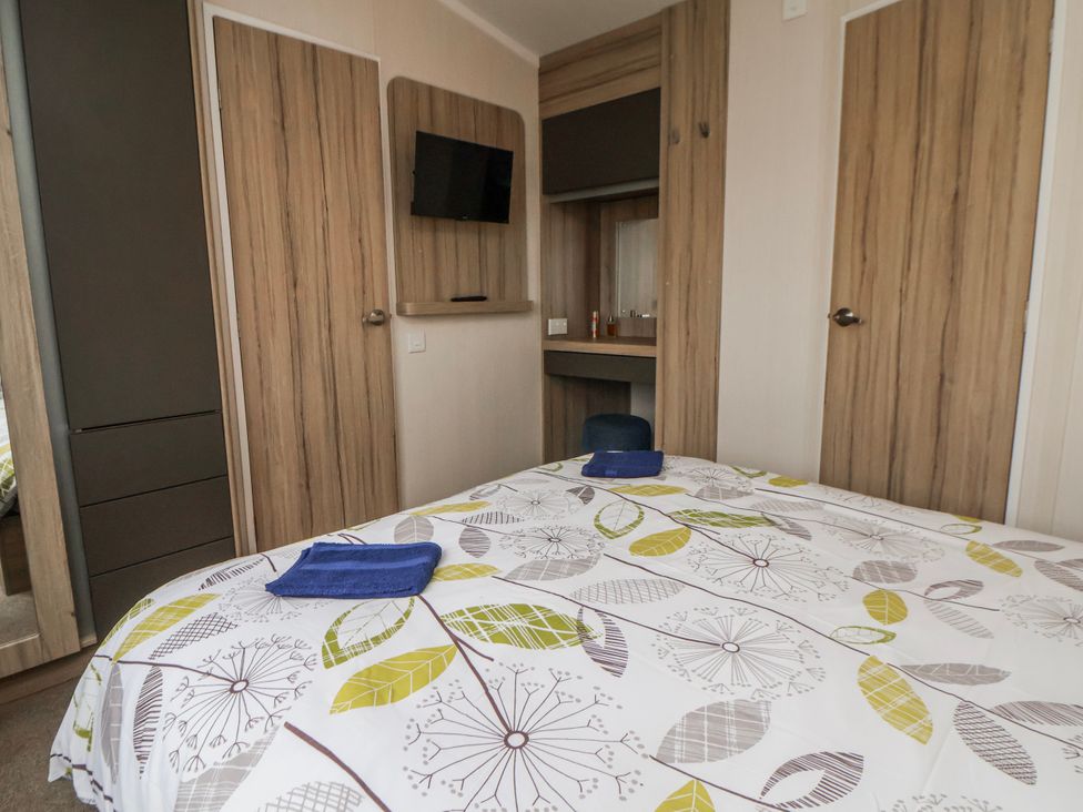 A bedroom with a bed and wardrobe at Chappie's Caravan 2.0 in Rhyl