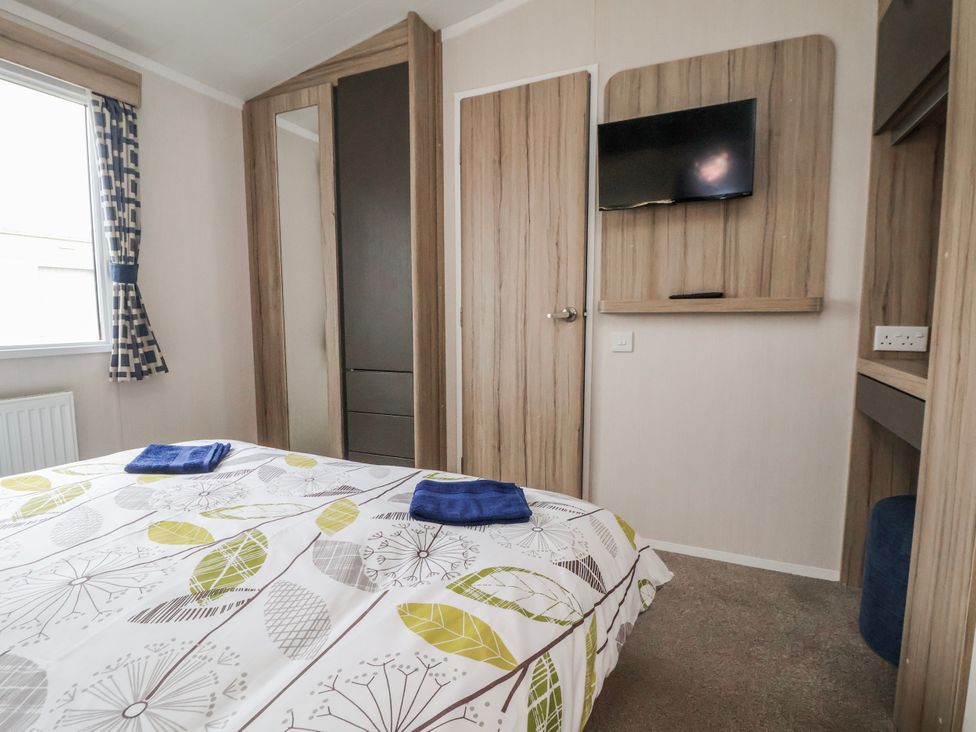 A bedroom with a bed and wardrobe at Chappie's Caravan 2.0 in Rhyl