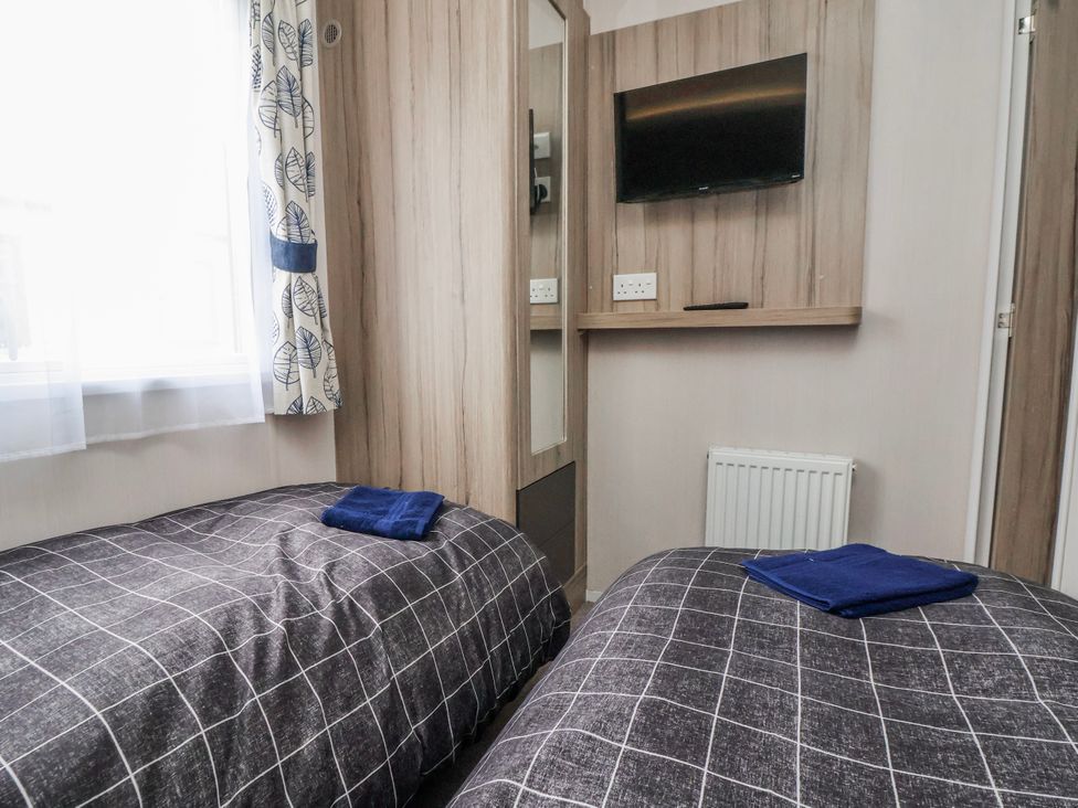 A bedroom with two beds and a television at Chappie's Caravan 2.0 in Rhyl