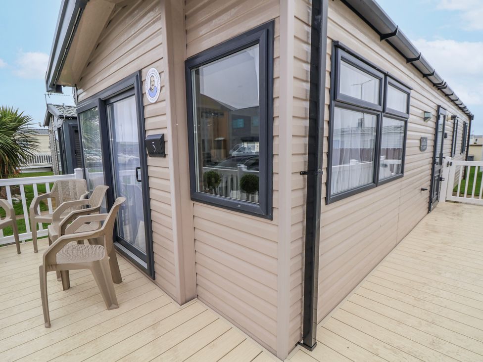 The exterior of a caravan with a deck and chairs at Chappie's Caravan 2.0 Rhyl