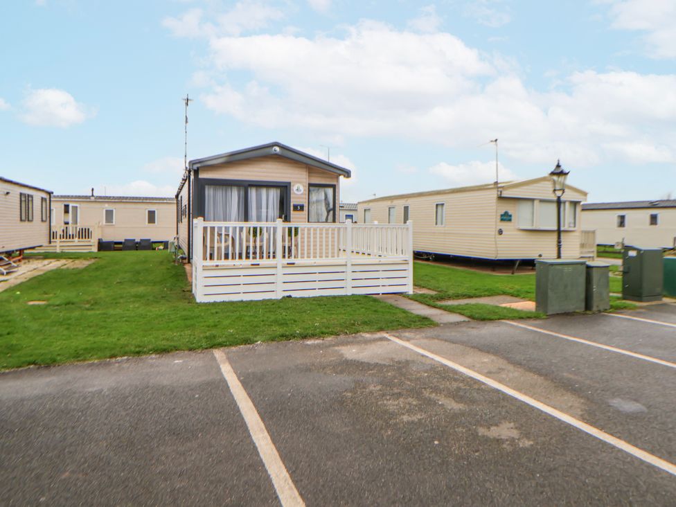 A caravan with a deck in a parking area at Chappie's Caravan 2.0 in Rhyl