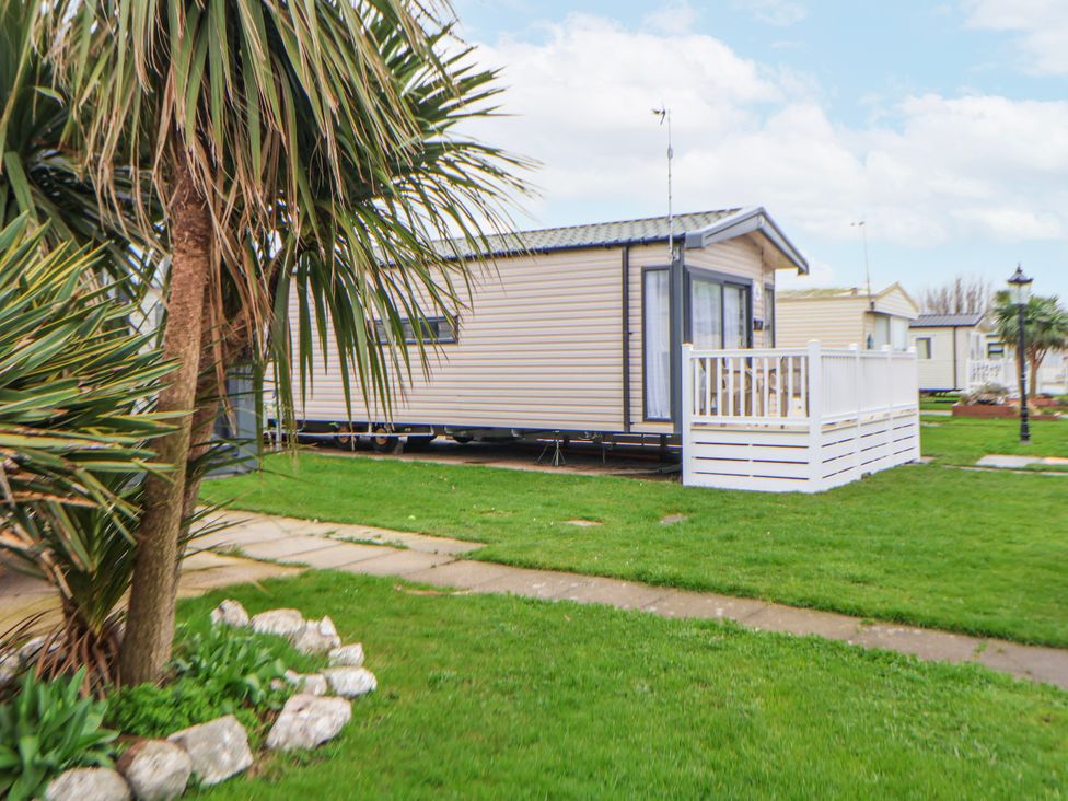 A caravan with a deck and palm tree at Chappie's Caravan 2.0 Rhyl