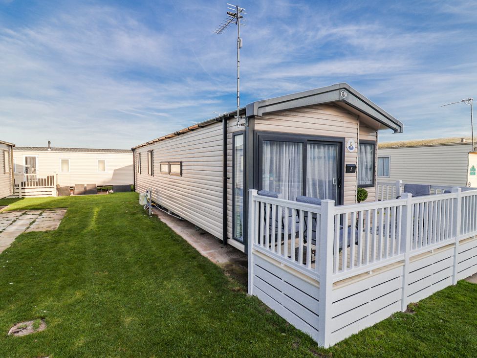 A caravan with decking and grass surrounding at Chappie's Caravan 2.0 Rhyl