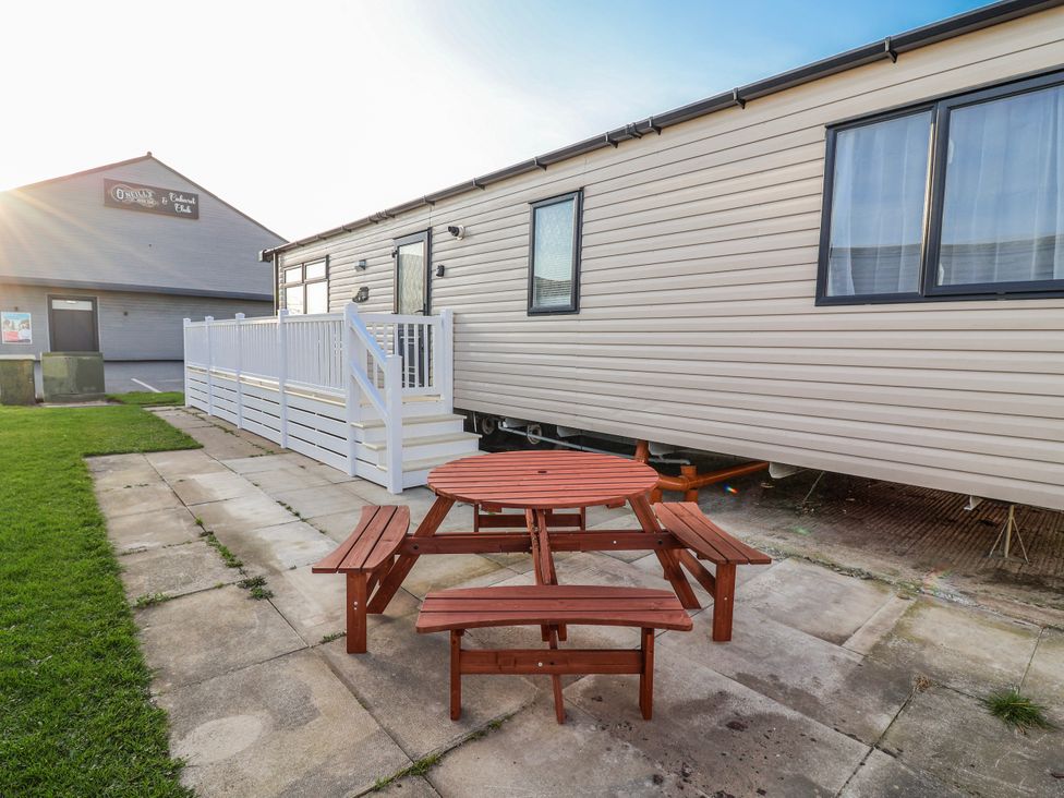 An outdoor space with a caravan and a picnic table at Chappie's Caravan 2.0 Rhyl