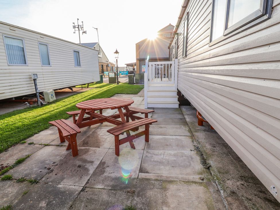 An outdoor seating area with a picnic table and benches at Chappie's Caravan 2.0 Rhyl