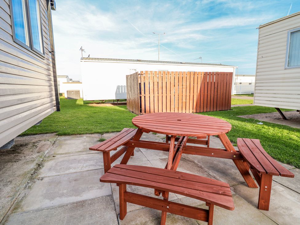 An outdoor area with a picnic table and benches at Chappie's Caravan 2.0 Rhyl