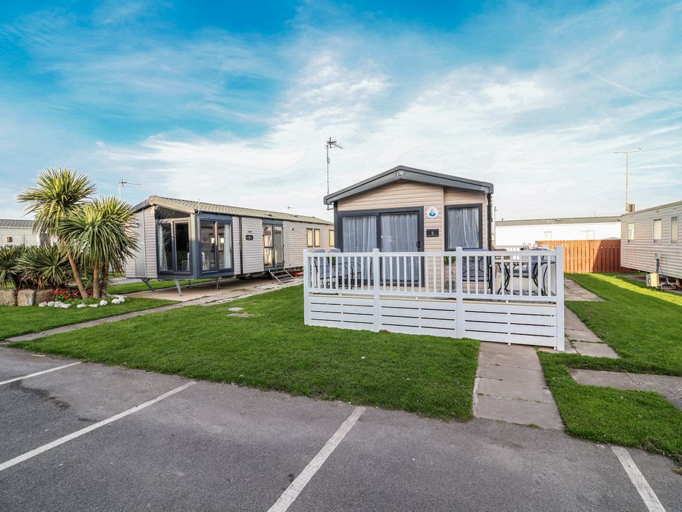 A caravan with a deck and grass area at Chappie's Caravan 2.0 in Rhyl