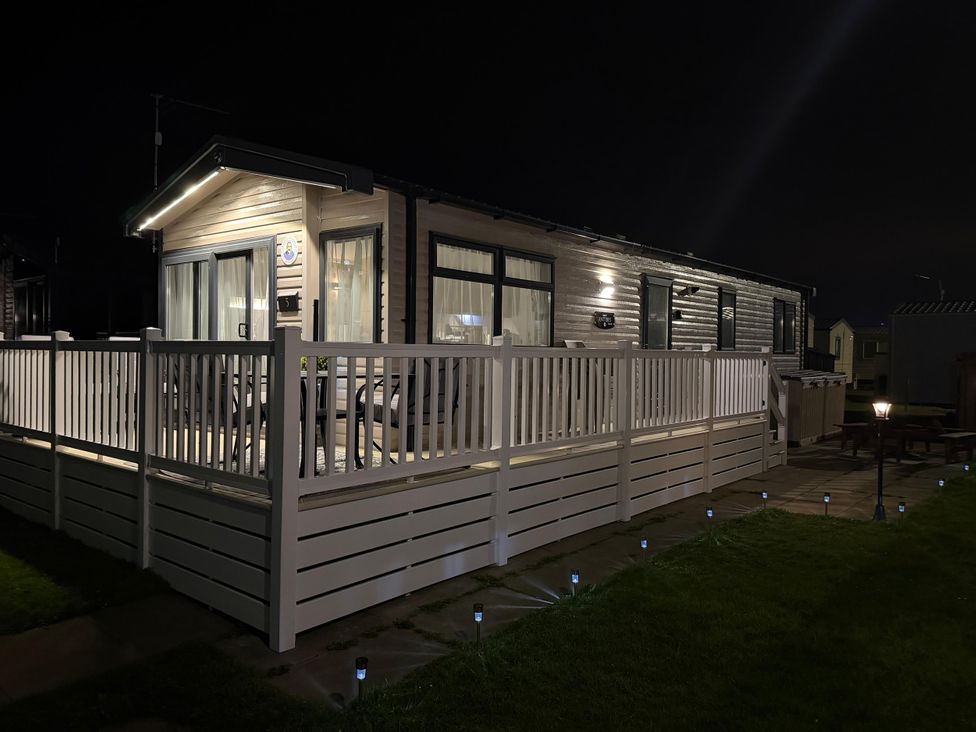 A caravan with a decking area and lights at Chappie's Caravan 2.0 Rhyl