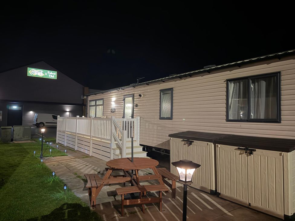 An outdoor area with a caravan and table at Chappie's Caravan 2.0 in Rhyl