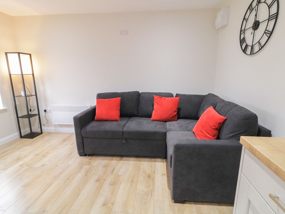 A living room with a gray sofa and a floor lamp at Binevenagh Point Cabin 