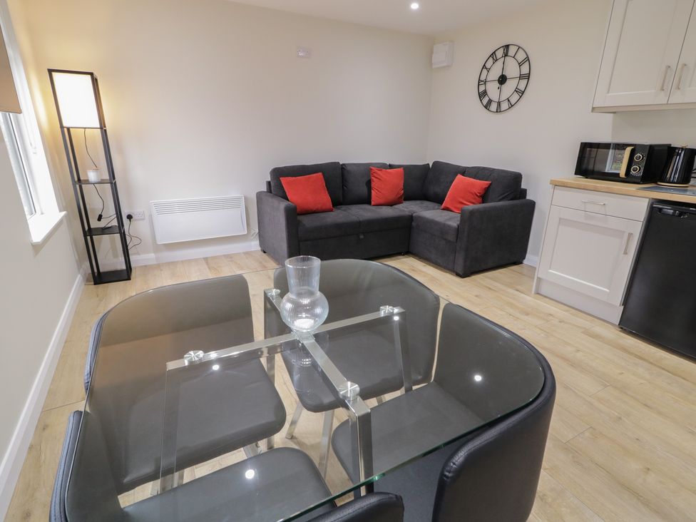A living room with a sofa a table and kitchen units at Binevenagh Point Cabin
