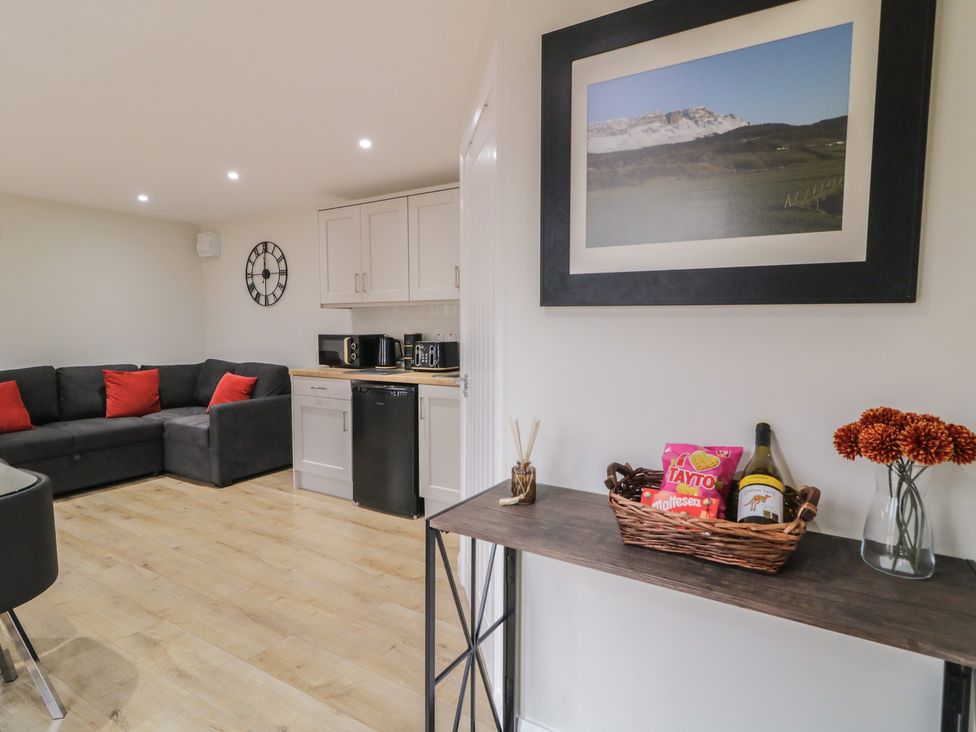 A living room with a sofa and kitchen area at Binevenagh Point Cabin