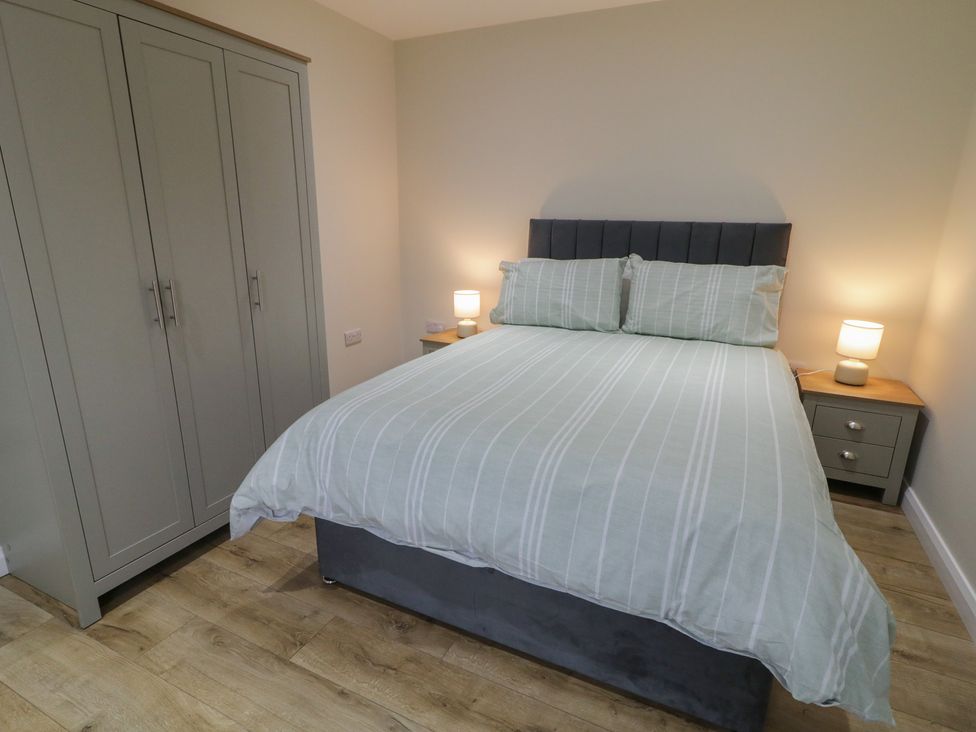 A bedroom with a bed, wardrobe, nightstand, and lamp at Binevenagh Point Cabin