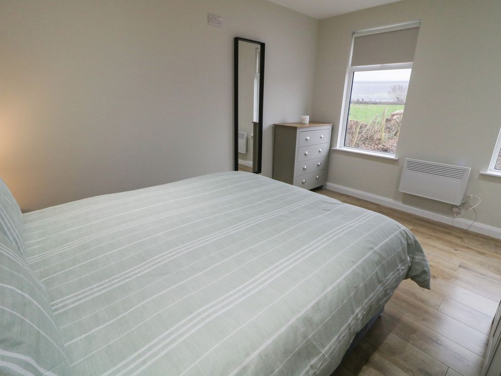 A bedroom with a bed and mirror at Binevenagh Point Cabin