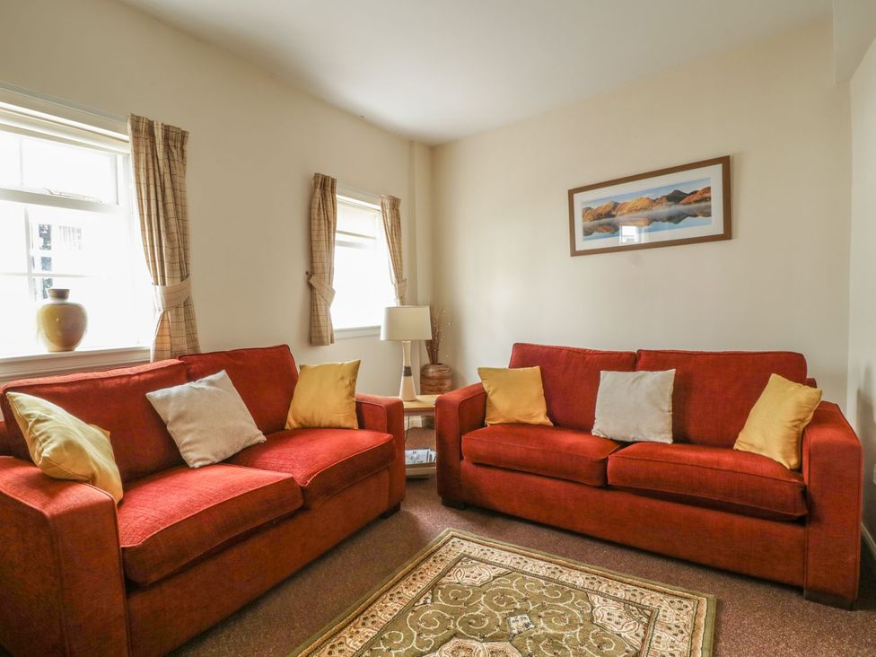 A living room with red sofas and a table at No 8- Farmhouse Retreat in Keswick