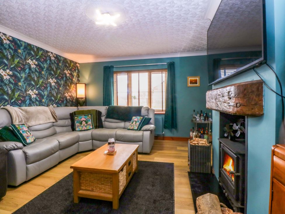 A living room with a sofa, coffee table and fireplace at 36 Cae Rhos in Holyhead